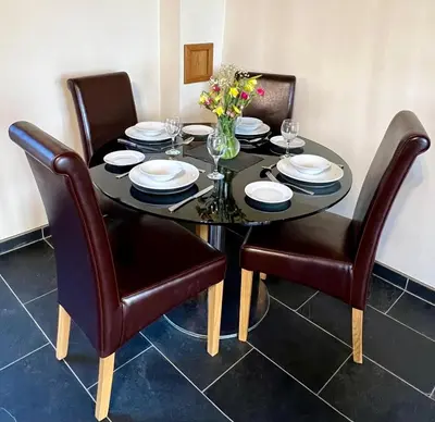 a dining room table with chairs and a black table with flowers at One-Bedroom Cottage in Snowdonia National Park in Dolgellau