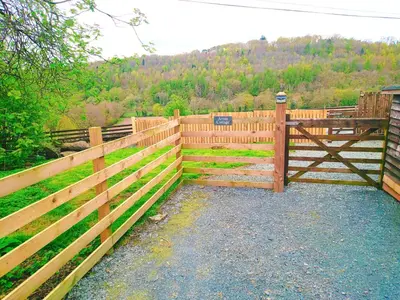 a wooden fence with a gate in a field at One-Bedroom Cottage in Snowdonia National Park in Dolgellau