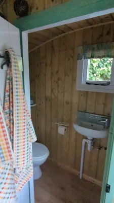a bathroom with a toilet and a sink and a window at Myndy The Shepherd's Hut in Church Stretton