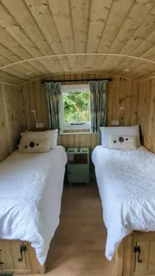 two beds in a small room with a window at Myndy The Shepherd's Hut in Church Stretton
