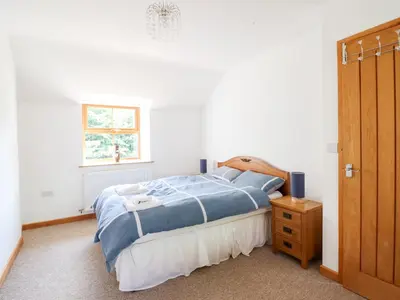 a bedroom with a bed with blue sheets and a window at Gwernffridd in Llanbrynmair
