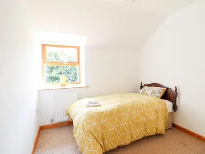 a bedroom with a bed with a yellow comforter and a window at Gwernffridd in Llanbrynmair