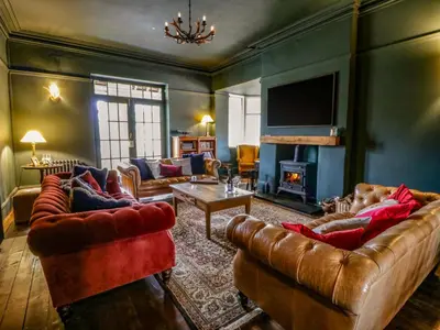 a living room with leather furniture and a fireplace at The Retreat at Glanrannell Park House in Llanwrda