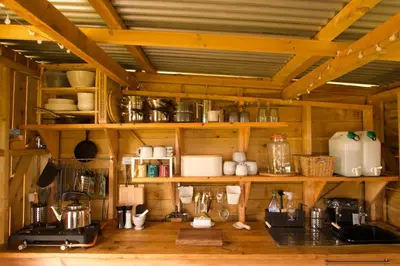 a kitchen with wooden walls and shelves with utensils at Glamping Pod - Sleeps 2 - Pets - Parking - Wifi in Llanon