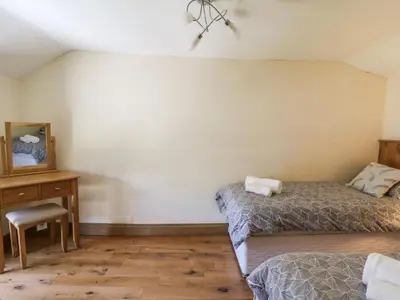 a bedroom with two beds and a table and a chair at Felin Gogoyan in Tregaron