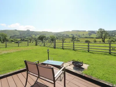 a deck with a table and chairs and a field at Bwthyn Bach Brefi in Tregaron