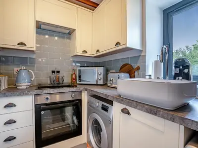 a kitchen with a sink and a washing machine at The Old Cowsheds 3 - Mynach - Uk49788 in Cribyn