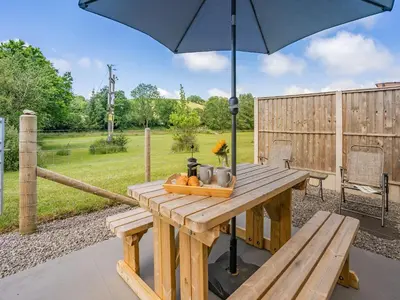 a wooden table with an umbrella on a patio at The Old Cowsheds 2 - Shippon - Uk49787 in Cribyn