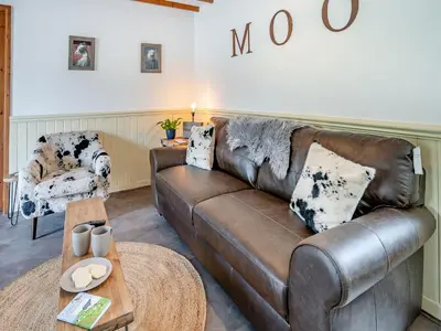 a living room with a brown leather couch at The Old Cowsheds 1- Dairy - Uk49786 in Cribyn