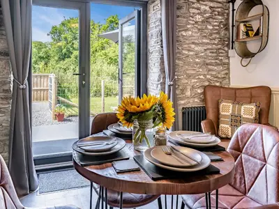 a dining room with a table with a vase of flowers at The Old Cowsheds 1- Dairy - Uk49786 in Cribyn