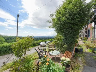 a patio with benches and a table with a view at Clee View Cottage in Ludlow