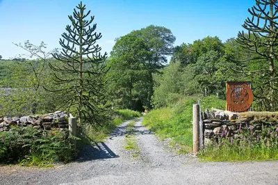 a dirt road with a fence and a sign at Scenic Pet Friendly Pod in Talybont Aberystwyth in Aberystwyth