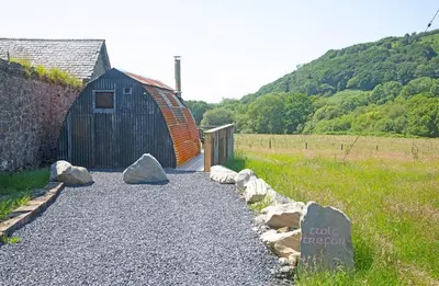 a barn and some rocks on a gravel road at Scenic Pet Friendly Pod in Talybont Aberystwyth in Aberystwyth