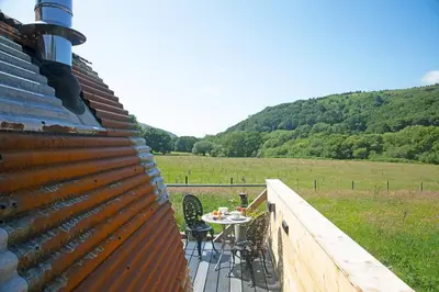 a table and chairs on a deck with a view of a field at Scenic Pet Friendly Pod in Talybont Aberystwyth in Aberystwyth