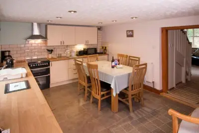 a kitchen with a table and chairs in a room at Ty Ffarm, Gogarth
