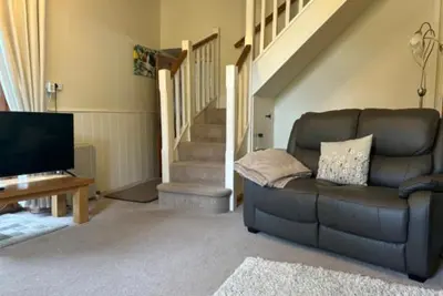 a living room with a couch and a television at Ty Ffarm, Gogarth