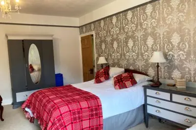 a bedroom with a bed with a red plaid blanket at Ty Ffarm, Gogarth