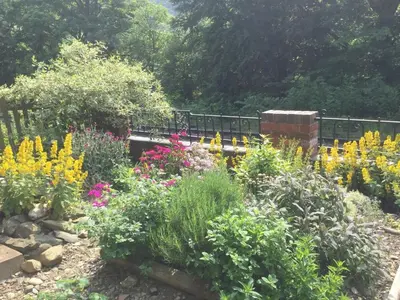 a garden with colorful flowers and a train at Outstanding Llangollen Riverside Apartment in Llangollen