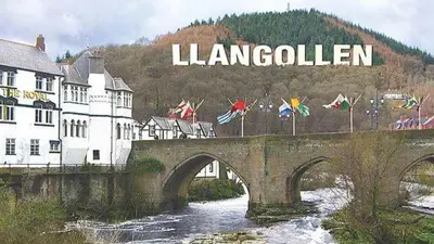 a bridge over a river with the wordolkien on it at Outstanding Llangollen Riverside Apartment in Llangollen