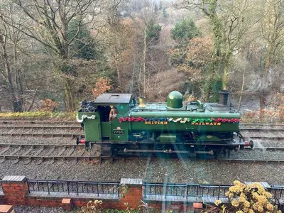a green train is on the tracks at Outstanding Llangollen Riverside Apartment in Llangollen