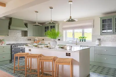 a kitchen with green cabinets and a kitchen island with stools at Llys y wawr Luxury Holiday Let in Aberystwyth