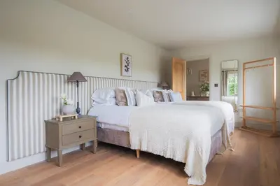a white bedroom with two beds and a night stand at Llys y wawr Luxury Holiday Let in Aberystwyth