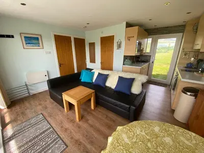 a living room with a black couch and a table at Snowdonia 1-Bed Chalet Sleeps 2 Stunning Views in Pennal