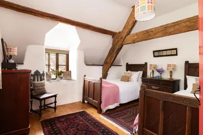 a bedroom with two beds in a room with beams at Ty Neuadd in Dolgellau