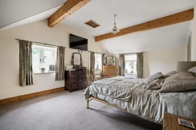 a bedroom with a large bed and windows at Priory cottage in Clifford