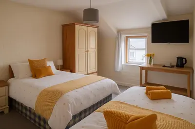 a bedroom with two beds and a tv on the wall at Ty Sunnymead Guesthouse in Aberystwyth
