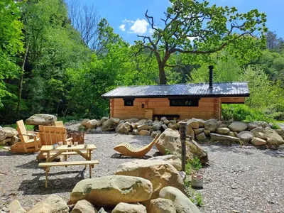 a log cabin with a picnic table and a bench at Woodcutters' Cabin Authentic Log Cabin Talybont Aberystwyth SY245DW in Aberystwyth