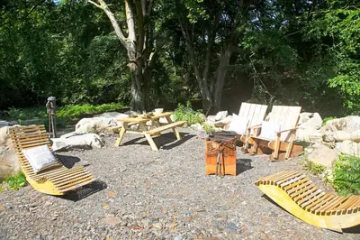 a group of chairs and a picnic table in a park at Woodcutters' Cabin Authentic Log Cabin Talybont Aberystwyth SY245DW in Aberystwyth