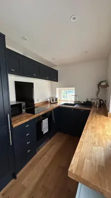 a kitchen with black cabinets and a wooden floor at Builth wells stay in Builth Wells