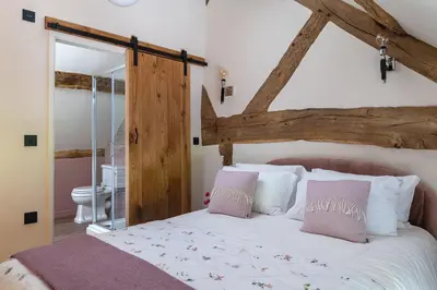 a bedroom with a large bed with white sheets and pink pillows at Swn y Nant in Glyn-Ceiriog