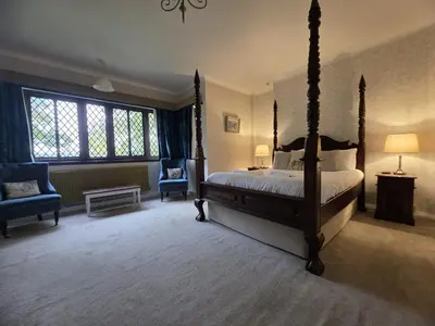 a bedroom with a four poster bed and two chairs at Caer Beris Hotel in Builth Wells