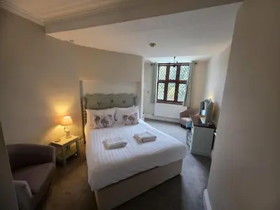 a bedroom with a bed and a couch and a television at Caer Beris Hotel in Builth Wells