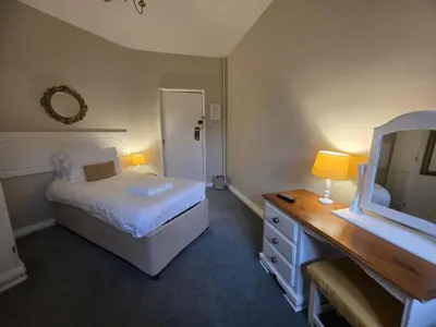 a bedroom with a bed and a dresser and a mirror at Caer Beris Hotel in Builth Wells
