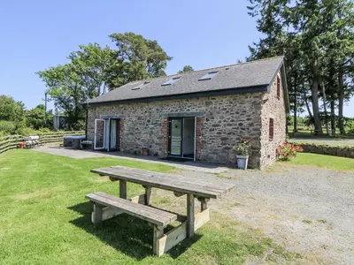 a picnic bench in front of a stone building at Little Penrhosgoch Barn in Llandrindod Wells