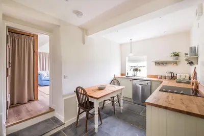 a kitchen with a wooden table and chairs in a room at Cosy cottage with stunning views, close to Ludlow in Bucknell