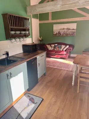 a kitchen with a sink and a table and a couch at The Robin, Arrowwood Self Catering in Kington