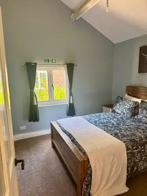 a bedroom with a bed and a window at The Robin, Arrowwood Self Catering in Kington