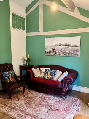 a living room with a leather couch and a chair at The Robin, Arrowwood Self Catering in Kington