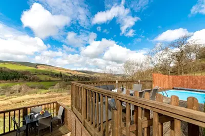 a deck with a pool and a table and chairs at Cae Madog Barn in Llanbrynmair