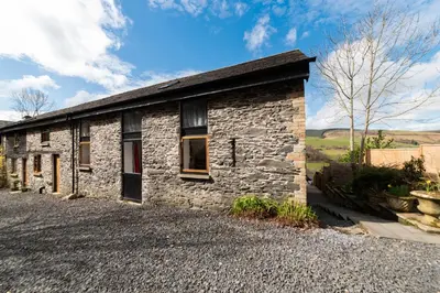 a stone house on the side of a road at Cae Madog Barn in Llanbrynmair