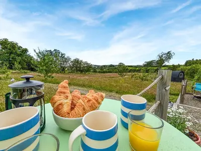 a table with a bowl of croissants and cups of orange juice at The Owl Pod - Uk50070 in Welshpool