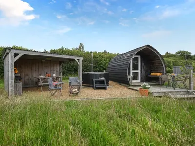 a woman sitting in a chair in front of a cabin at The Hedgehog Pod - Uk50067 in Welshpool