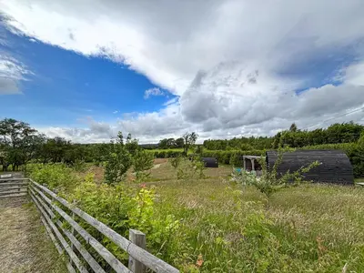 a field with a fence and an old barn at The Hedgehog Pod - Uk50067 in Welshpool