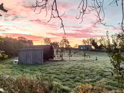 a barn in a field with a sunset in the background at The Hedgehog Pod - Uk50067 in Welshpool