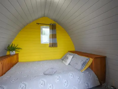 a bedroom with a bed in a yellow wall at The Hedgehog Pod - Uk50067 in Welshpool