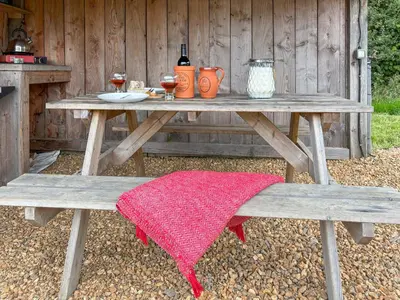 a picnic table with two benches and a red blanket at The Hedgehog Pod - Uk50067 in Welshpool